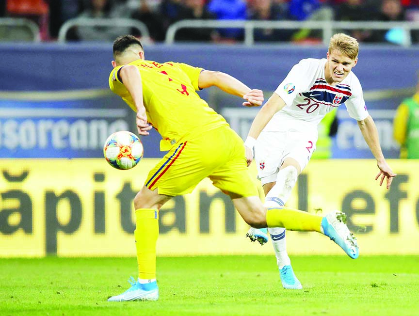 Romania's Ionut Nedelcearu (left) tries to block a shot from Norway's Martin Odegaard during the Euro 2020 group F qualifying soccer match between Romania and Norway on the National Arena stadium in Bucharest, Romania on Tuesday.