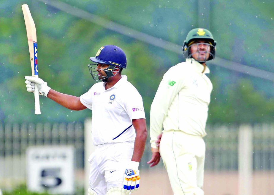 India's Rohit Sharma (left) raises his bat to celebrate scoring a century during first day of the third and last cricket Test match between India and South Africa in Ranchi, India on Saturday.