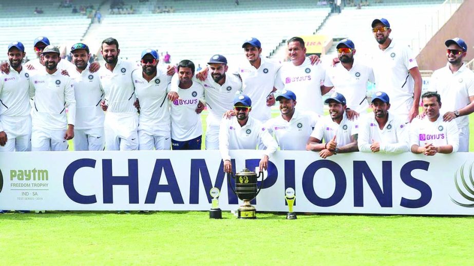 Members of Indian team pose with the winners trophy as captain Virat Kohli (center) flashes victory sign after their win in the fourth day of third and last cricket Test match between India and South Africa in Ranchi, India on Tuesday. India won the serie