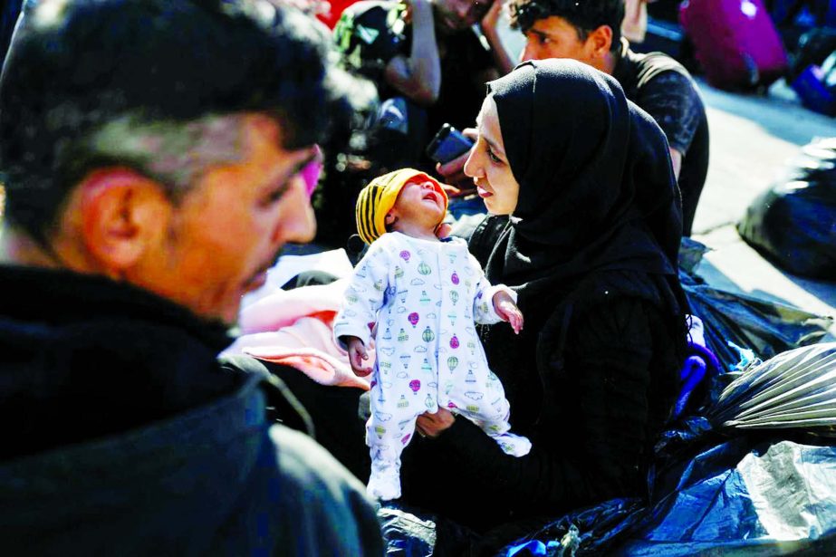 Salwa Saleh, 19, from Syria holds her ten-day-old baby as she waits to be transferred to camps on the mainland, at the port of Elefsina near Athens Greece on Tuesday.