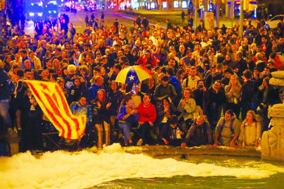 Protesters hold a Catalan pro-independence 'Estelada' flag and pour soap in a public fountain during a demonstration at the Placa d'Espana square called by the local Republic Defence Committees (CDR).