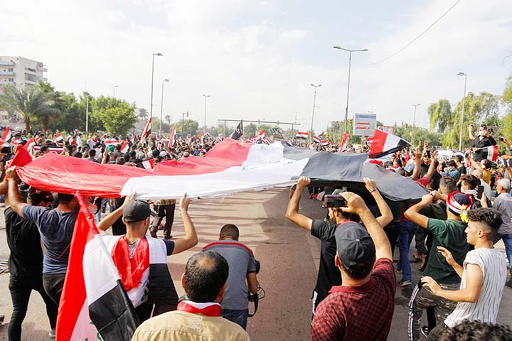 Demonstrators carry huge Iraqi flags during a protest over corruption, lack of jobs, and poor services, in Baghdad, Iraq.