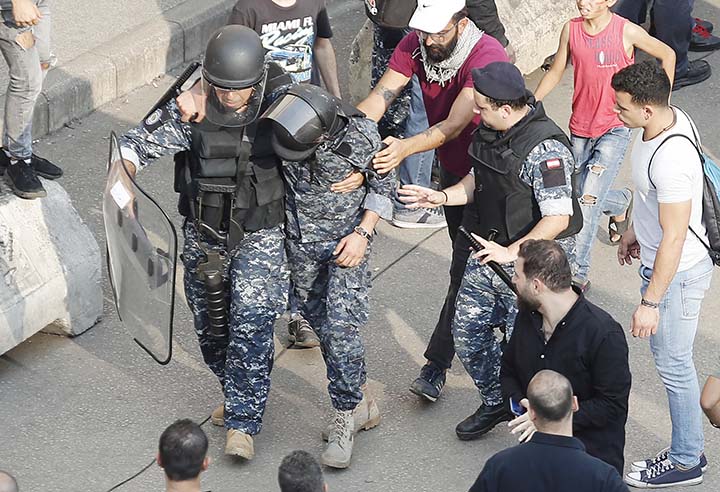 A Lebanese riot policeman, left, carries his injured comrade, center, after a clashes erupted between Hezbollah supporters and anti-government protesters during a protest near the government palace, in downtown Beirut, Lebanon on Friday.