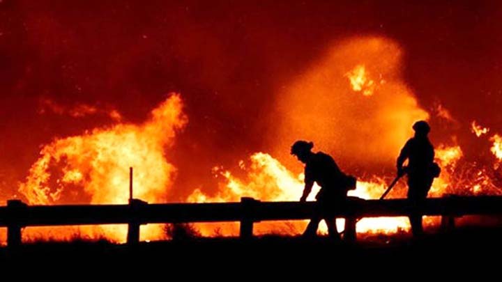 Firefighters battle a fire, as a wind driven wildfire continues to burn in Canyon Country north of Los Angeles, California.
