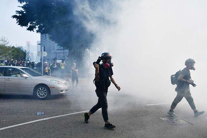 Clouds of acrid smoke wafted across streets usually packed with tourists, including outside the landmark colonial-era Peninsula Hotel, as protesters and police clashed.