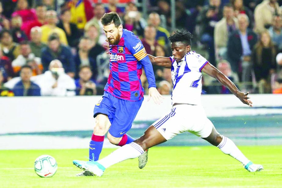 Barcelona's Lionel Messi (left) controls the ball past Valladolid's Mohammed Salisu during the Spanish La Liga soccer match between FC Barcelona and Valladolid CF at the Camp Nou stadium in Barcelona, Spain on Tuesday.
