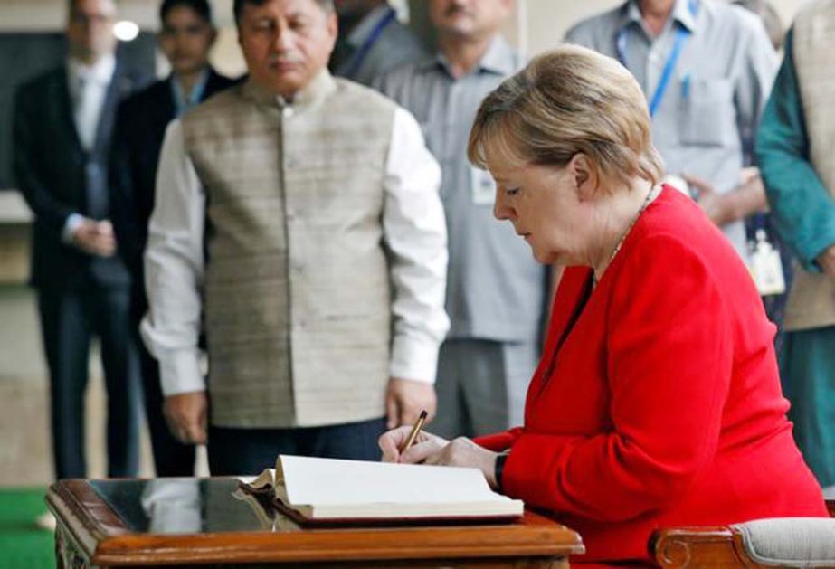 German Chancellor Merkel signs the visitors book during her visit to the Mahatma Gandhi Memorial at Rajghat in New Delhi