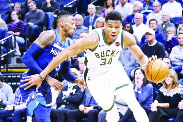 Milwaukee Bucks' Giannis Antetokounmpo (right) of Greece, drives around Minnesota Timberwolves' Robert Covington in the first half of an NBA basketball game in Minneapolis on Monday.