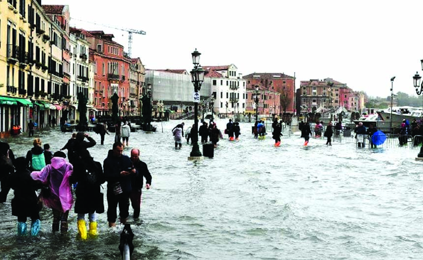 People wade through water during a high tide, in Venice on Wednesday. The high-water mark hit 187 centimeters (74 inches) late Tuesday, Nov. 12, 2019, meaning more than 85% of the city was flooded.