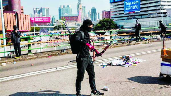 A protester with a bow and arrows stands on a barricaded street outside The Hong Kong Polytechnic University in Hong Kong on Friday.