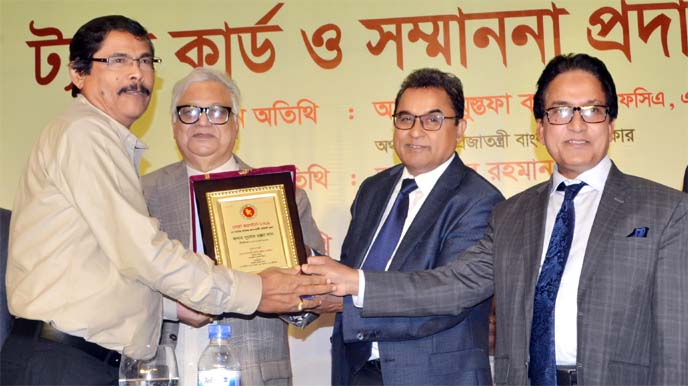 Finance Minister A H M Mustafa Kamal handing over crest & Tax Card to Babu Subodh Ranjon Das for being the highest taxpayer in Narsingdi at the Tax Card & Award Giving Ceremony at Hotel Radisson Blu Dhaka Water Garden in the city on Friday.