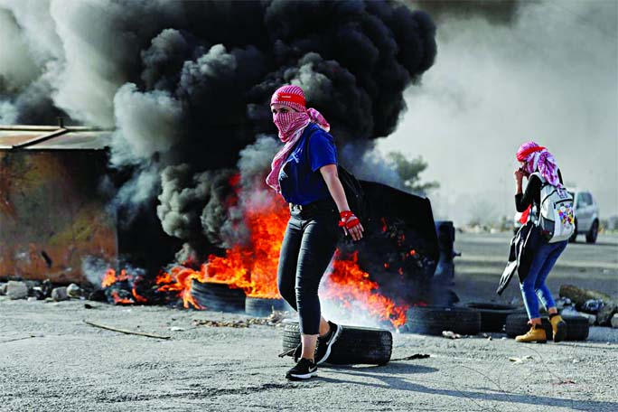 A female Palestinian demonstrator is seen in front of burning tires during an anti-Israel protest near the Jewish settlement of Beit El in the Israeli-occupied West Bank on Saturday.