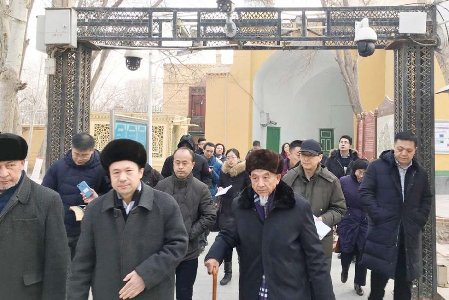 Imams and government officials pass under security cameras as they leave the Id Kah Mosque during a government organised trip in Kashgar, Xinjiang Uighur Autonomous Region, China.