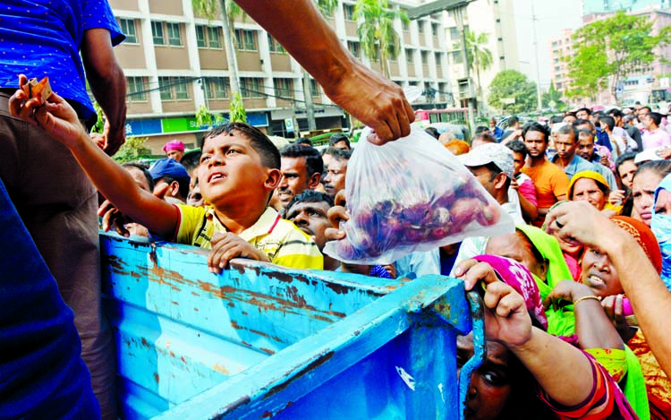 A little boy appealing to a salesman with money to get onion from a makeshift truck sale point run by state-run Trading Corporation of Bangladesh (TCB) set up at Motijheel C/A in Dhaka on Sunday.