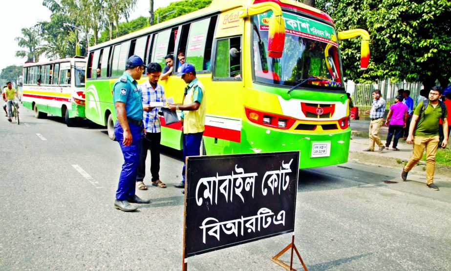 A traffic sergeant verifying documents from a bus driver during a mobile court of Bangladesh Road Transport Authority (BRTA) operated at Manik Mia Avenue in the capital on Monday.