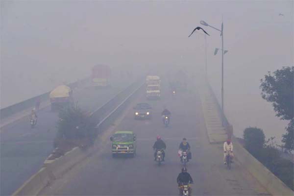 Commuters drive amid heavy smog conditions in Lahore.