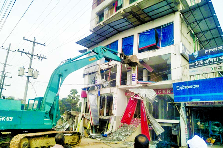A bulldozer knocks down an eight-story building, which was built occupying Dhaka-Aricha highway in Savar during an eviction drive conducted by the Roads and Highways Department (RHD) on Monday.