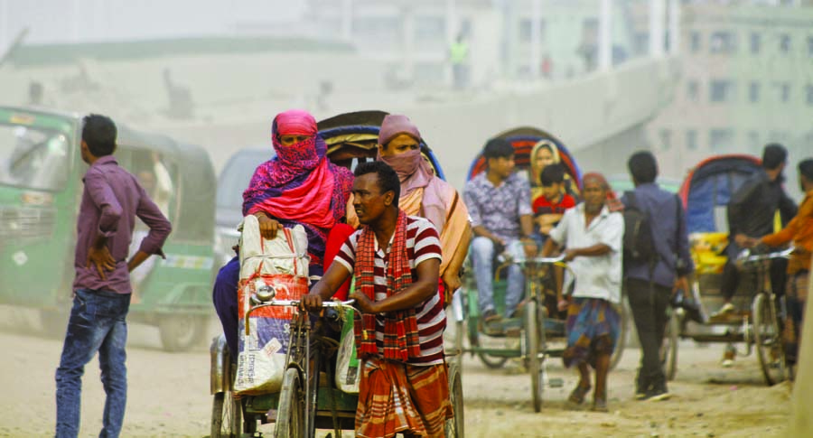 Covering their faces with scarf, two women passing through the Postogola road on Tuesday as dust gather all around amid rising air pollution in Dhaka with the advent of winter.