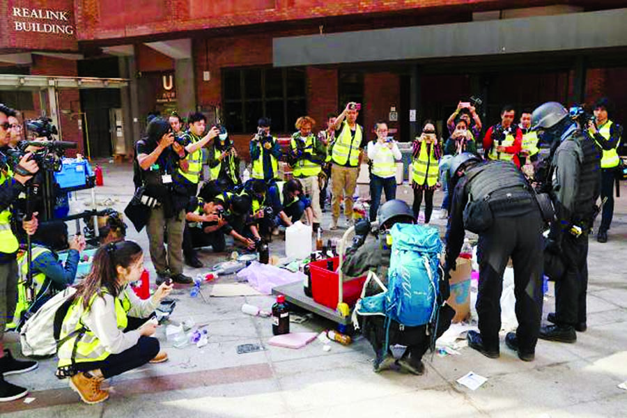 Members of a safety team established by police and local authorities assess and clear unsafe items, next to the media, at the Hong Kong Polytechnic University (PolyU) in Hong Kong, China, on 28 November 2019. Internet photo