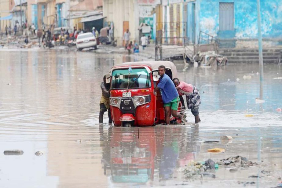 Somali men push their rickshaw through flood waters after rainfall in Mogadishu, Somalia.