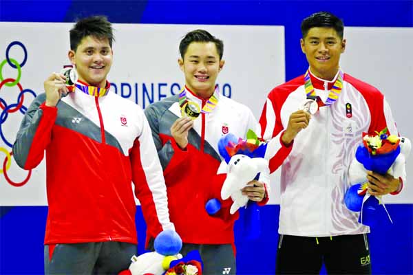 Gold medalist Singapore's Tzen Wei Teong (center) poses with silver medalist Singapore's Joseph Schooling (left) and bronze medalist Indonesia Glenn Sutanto (right) during awarding ceremonies for the men's 50m butterfly final during swimming competitio