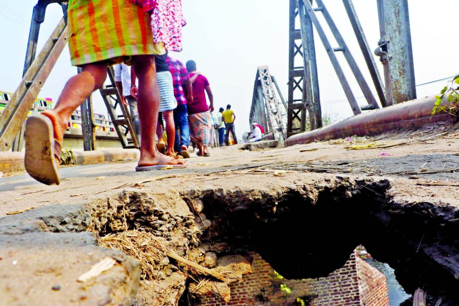 People pass though a big hole developed on Aminbazar's old bridge in Savar putting their lives at risk. This photo was taken on Sunday.