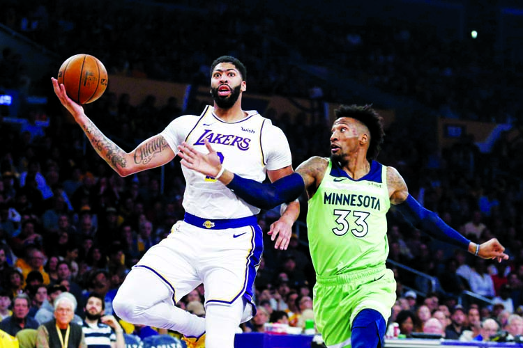 Los Angeles Lakers' Anthony Davis (3) drives to basket while defended by Minnesota Timberwolves' Robert Covington (33) during the first half of an NBA basketball game in Los Angeles on Sunday.