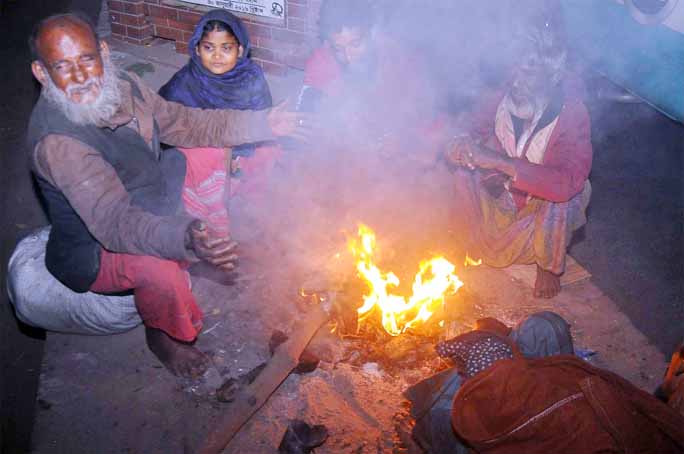 Poor people at Chattogram Old Rail Station warming themselves by burning straws yesterday.