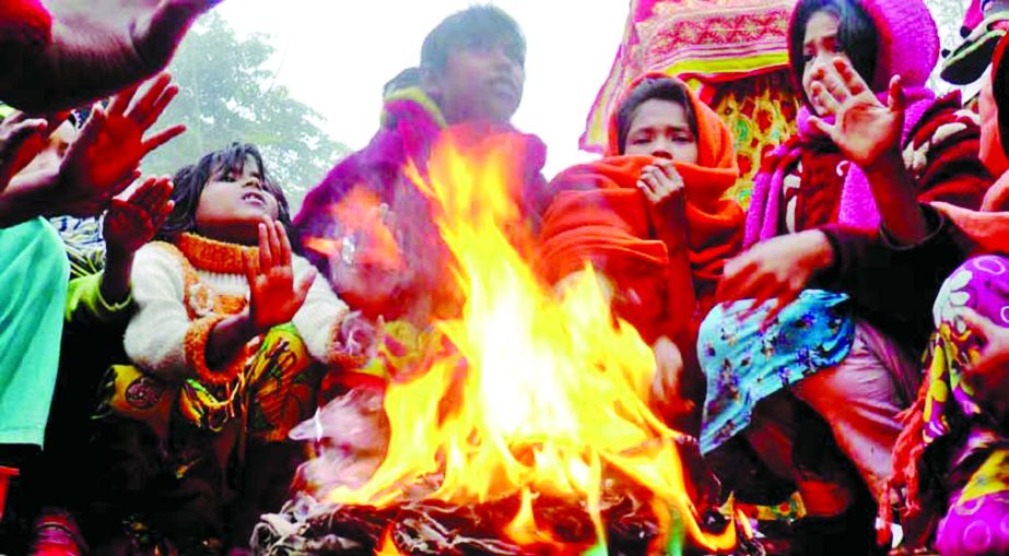 All gathered beside a fire to get warmth at Kazla in Rajshahi during the cold wave that sweeps the region on Thursday.