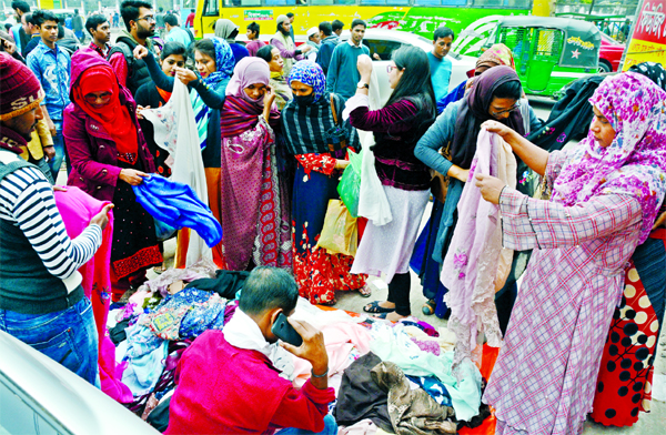 As winter sets in, people are seen bargaining with hawkers for buying warm clothes at makeshift shops on a footpath in front of New Market in Dhaka on Friday.
