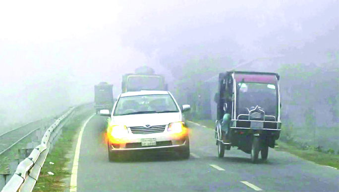 Vehicles on Dhaka-Kurigram Highway keeping their headlights active amid continued dense fog.