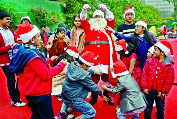 A Santa Claus distributing chocolates to kid at the Christmas celebration at Hotel Sonargaon in Dhaka on Wednesday.