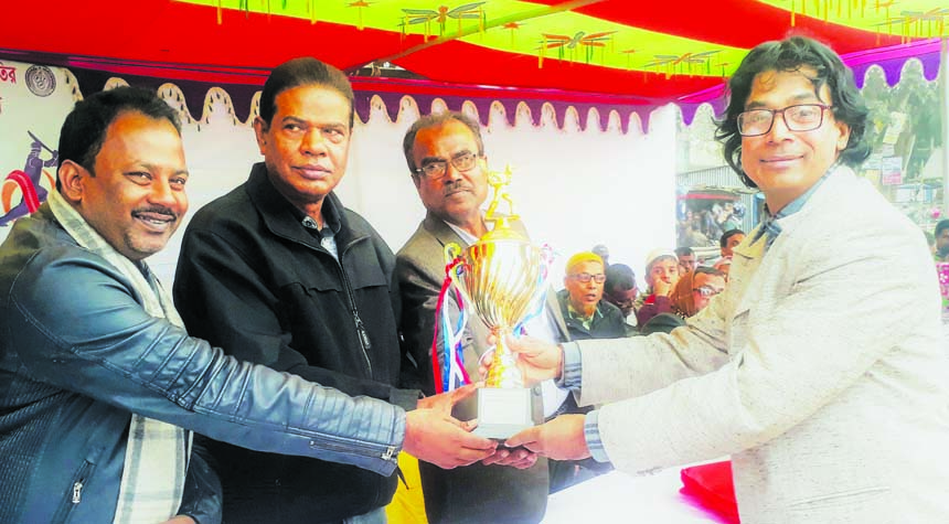 Former national athlete Md Altaf Hossain, Coach of Singair Government High School receiving the champions trophy in the Cricket Competition of 49th Bangladesh National School, Madrasa and Technical Education Sports Competition from Freedom Fighter Mushfiq