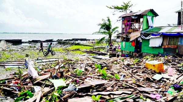 Residents walk past a house damaged during Typhoon Phanfone in Tacloban, Leyte province in the central Philippines.