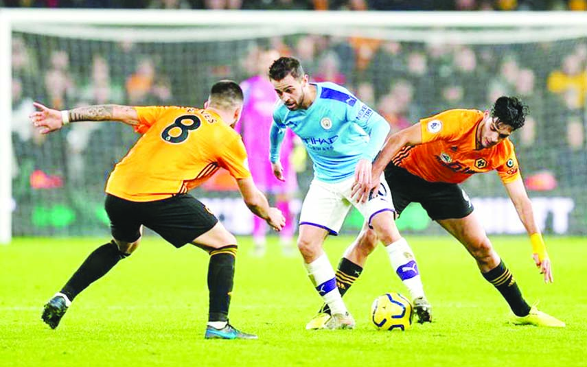 Wolverhampton Wanderers' Raul Jimenez (right) and Ruben Neves (left) in action with Manchester City's Bernardo Silva (center) during the English Premier League soccer match between Wolverhampton and Manchester City at Molineux Stadium in Wolverhampto