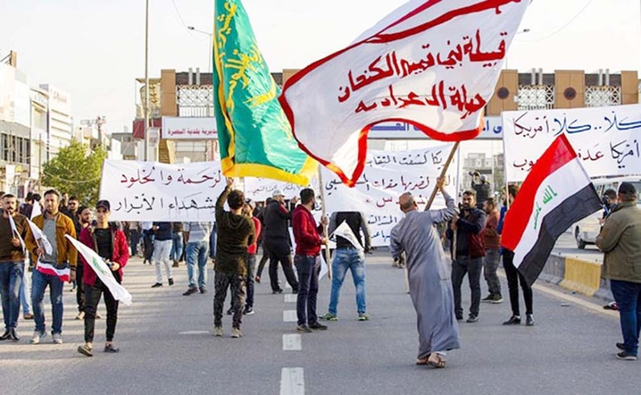 Protesters and militia fighters gather to condemn air strikes on bases belonging to Hashed al-Shaabi, outside the main gate of the US Embassy in Baghdad.