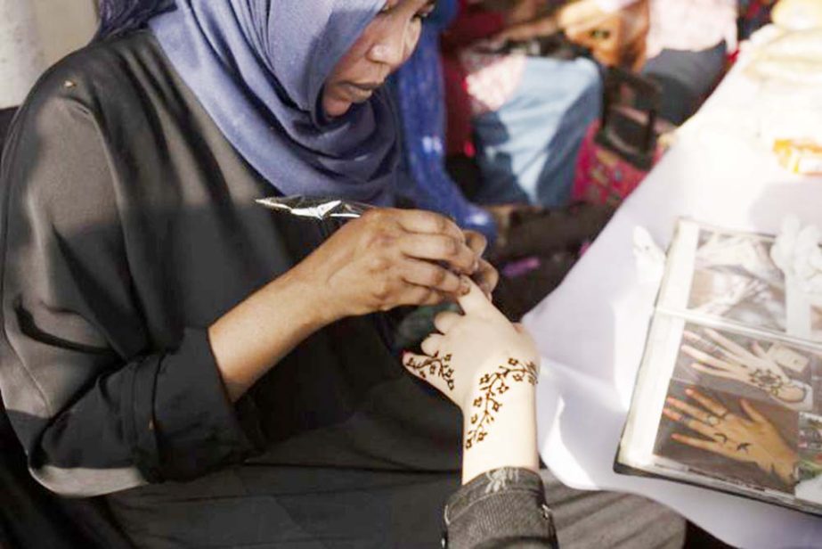 A Sudanese woman applies henna to a Yemeni girl's hand during an event marking the U.N.'s International Refugee Day, in Cairo, Egypt.