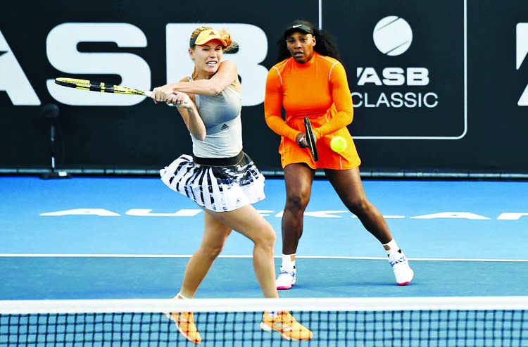 Denmark's Caroline Wozniacki plays a backhand as United States' Serena Williams looks on during their first round doubles match against Japan's Nao Hibino and Makoto Ninomiya at the ASB Classic in Auckland, New Zealand on Monday.