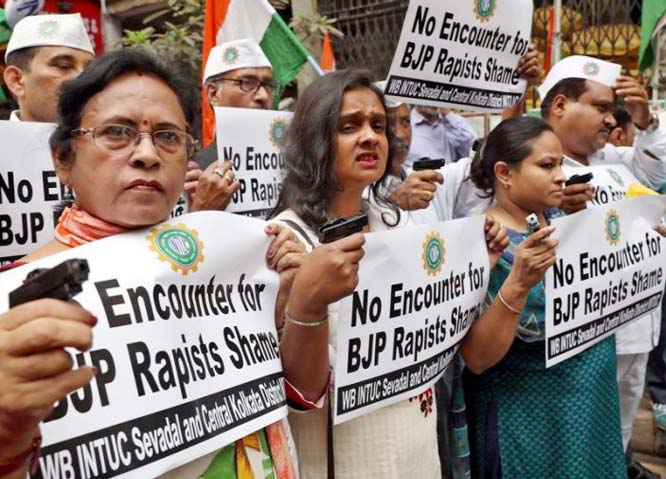 Activists from Indian National Trade Union Congress Seva Dal hold toy pistols and placards during a protest following the death of a 23-year-old rape victim, in Kolkata