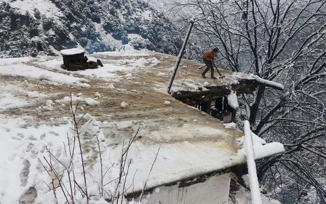 A boy clears a snow-covered roof of his family house after a heavy snowfall in Neelum Valley near line of control (LoC), Pakistan, Jan 13, 2020. REUTERS