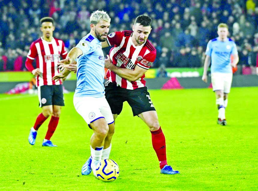 Manchester City's Sergio Aguero (centre) and Sheffield United's Enda Stevens challenge for the ball during the English Premier League soccer match between Sheffield United and Manchester City at Bramall Lane in Sheffield of England on Tuesday.