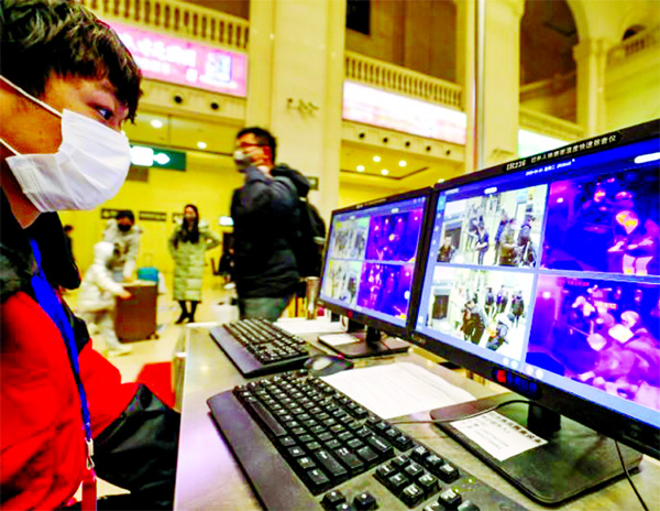 A staff member wearing a mask monitors thermal scanners that detect temperatures of passengers at the security check inside the Hankou Railway Station in Wuhan, Hubei Province.