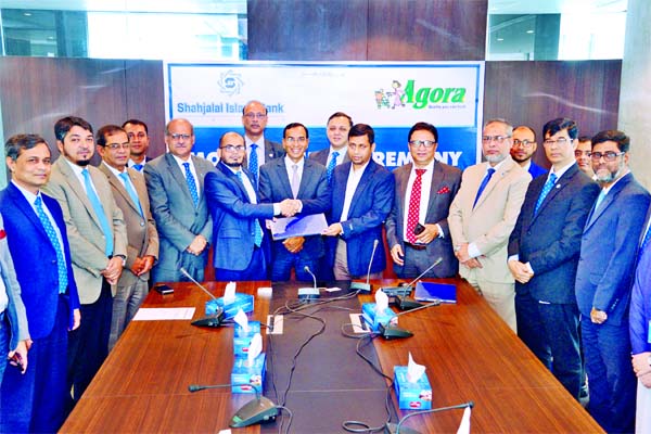 M Shahidul Islam, SVP of Shahjalal Islami Bank Limited and Farhad F. Ahmad, CEO of Agora (Super Shop) Limited, exchanging a MoU signing document at the bank's head office in the city on Thursday. Under the deal, all credit card holders of the bank will b