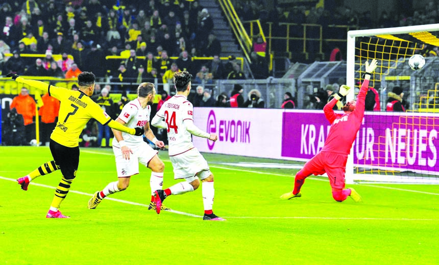 Dortmund's Jadon Sancho (left) scores his side's third goal against Cologne's goalkeeper Timo Horn (right) during the German Bundesliga soccer match between Borussia Dortmund and FC Cologne at Dortmund in Germany on Friday.