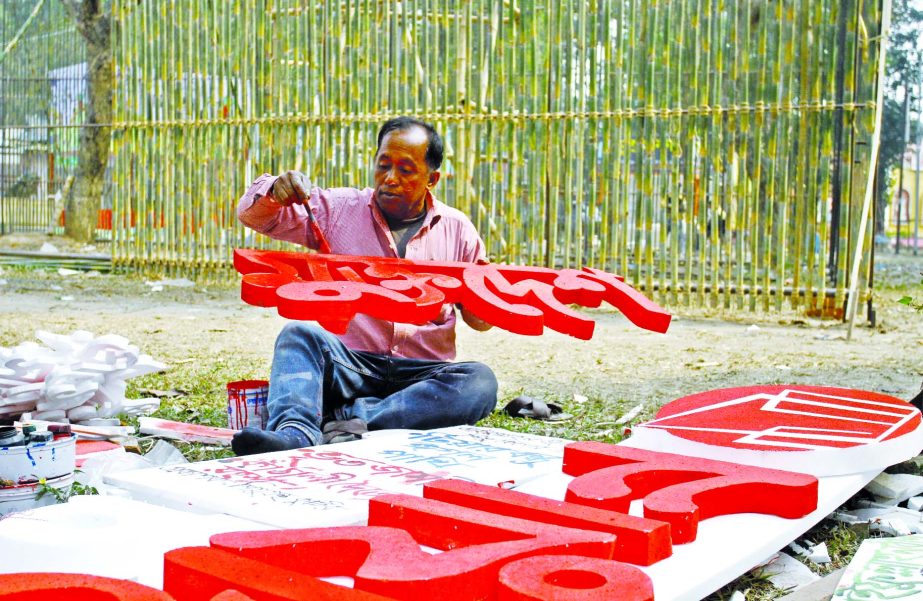 A man paints sign of a stall at the capital's Suhrawardy Udyan on Tuesday, as part of the preparations for the month-long Amar Ekushey Boi Mela to be opened on February 2.