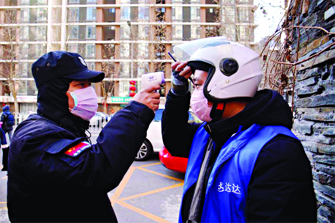 A security officer takes body temperature measurement of a delivery worker at a residential compound in Beijing, China as the country is hit by an outbreak of the new Coronavirus on Saturday.