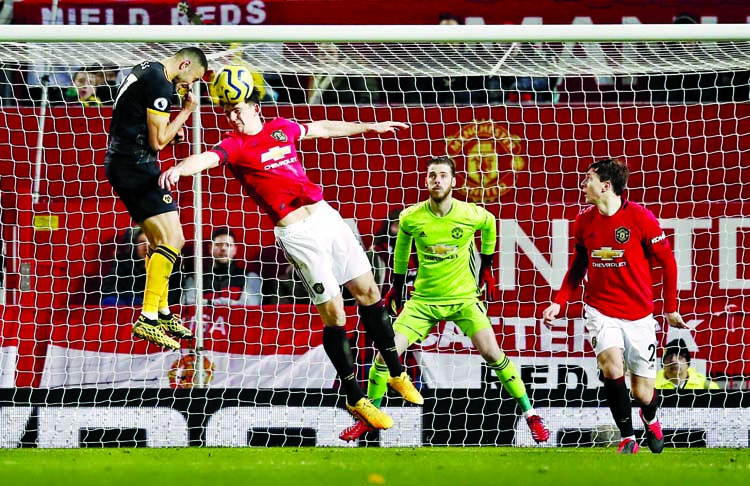 Manchester United's Harry Maguire heads the ball clear under pressure from Wolverhampton Wanderers' Romain Saiss during the English Premier League soccer match between Manchester United and Wolverhampton Wanderers at Old Trafford in Manchester of Engla