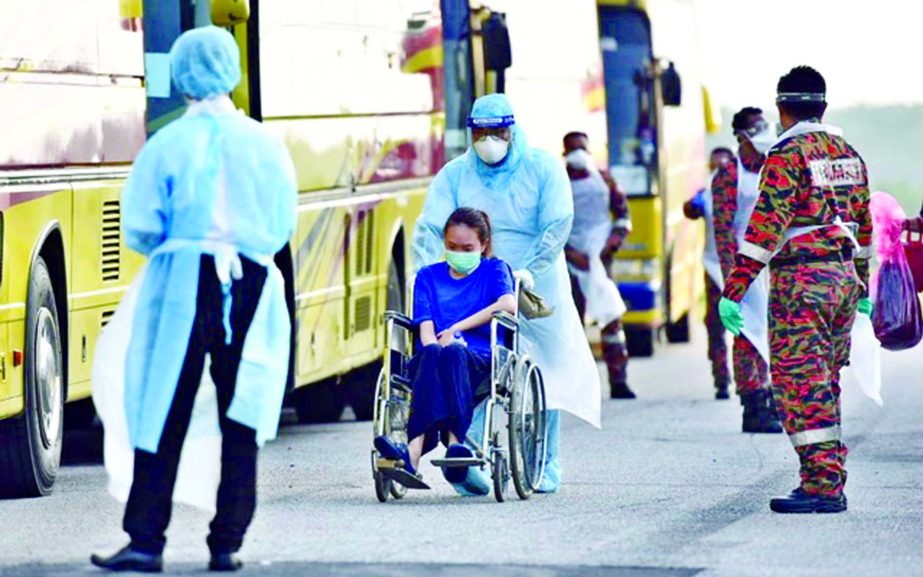 An evacuated Malaysian national from Wuhan is wheeled onto a bus by health officials in protective suits after arriving at Kuala Lumpur International Airport in Sepang of Malaysia on Tuesday.