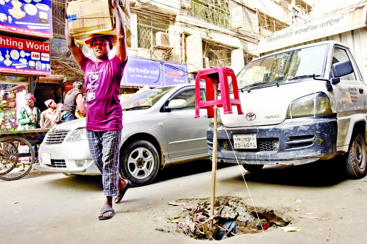 A stick sets down on an open manhole on a road at Noabpur Road in Dhaka to notify imminent risk of passing through the spot. The photo was taken on Tuesday.