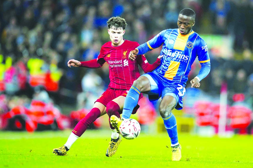 Liverpool's Neco Williams (left) fights for the ball with Shrewsbury Town's Daniel Udoh during the English FA Cup Fourth Round replay soccer match between Liverpool and Shrewsbury Town at Anfield Stadium in Liverpool of England on Tuesday.